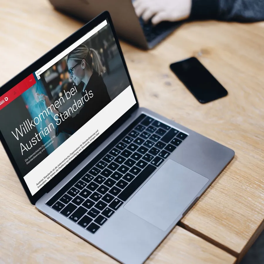 Website von Austrian Standards auf einem Laptop auf einem Holztisch