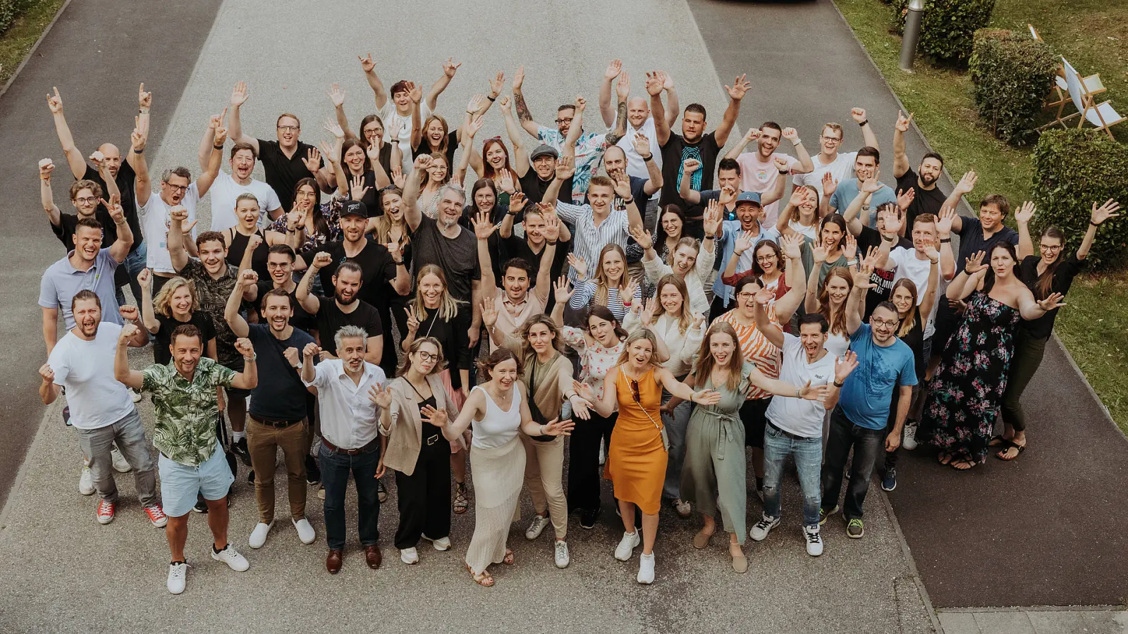 Gruppenfoto der E-CONOMIX GROUP: rund 70 Mitarbeitende von oben fotografiert, mit erhobenen Armen
